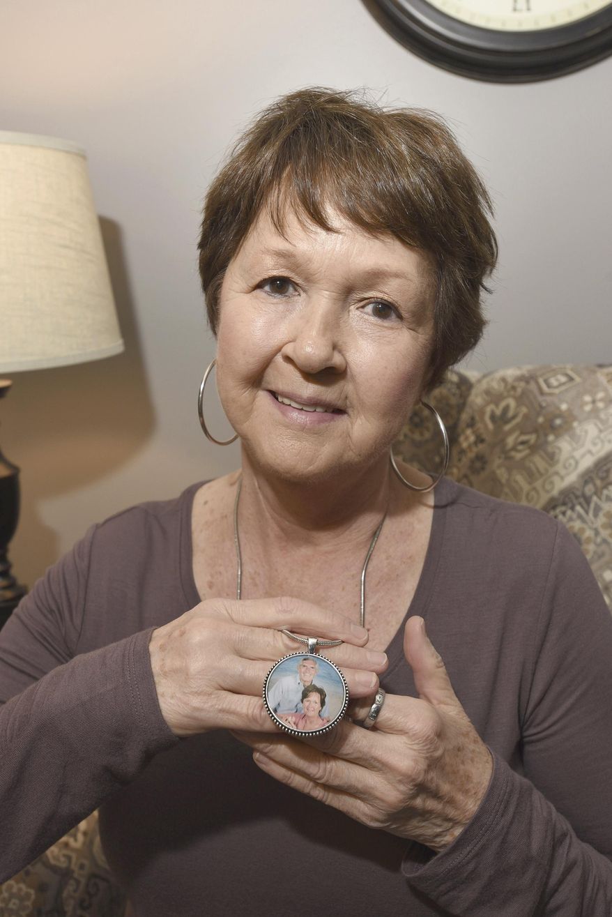FIle - In this Jan. 30, 2019, file photo, Linda Hagan, facilitator with Owensboro Survivors of Suicide (SOS) Bereavement Support Group, holds a pendant she wears around her neck of herself and her late husband, Tom Hagan, in her home in Owensboro, Ky. Tom Hagan committed suicide on Oct. 5, 2012. (Alan Warren/The Messenger-Inquirer via AP)
