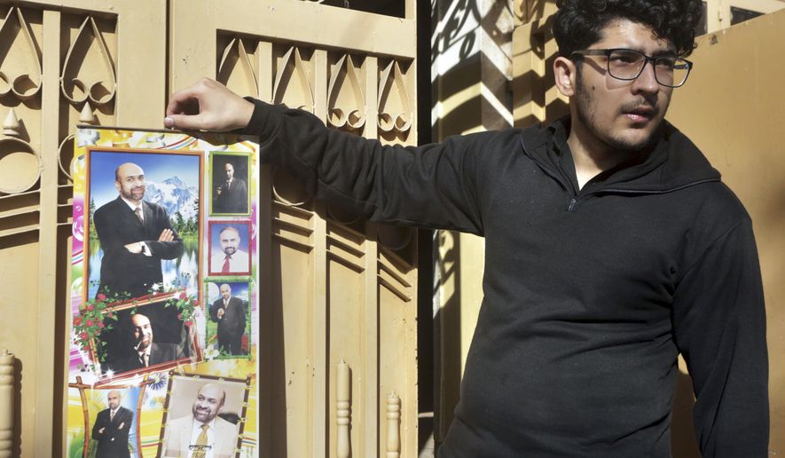 Osama Rizi, son of a journalist Rizwan-ur-Rehman Razi, displays a calendar with the pictures of his father outside his residence in Lahore, Pakistan, Saturday, Feb. 9, 2019. Pakistani authorities detained a rights activist who led a protest and a journalist Razi who allegedly criticized state agencies on traditional and social media, officials said Saturday. (AP Photo/K.M. Chaudary)