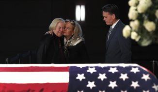 Rep. Debbie Dingell, D-Mich., center, consoles former Rep. Candice Miller, R-Mich., as Macomb County executive Mark Hackel, right, looks on at the casket of her husband and former Rep. John Dingell, lying in repose in Dearborn, Mich., Monday, Feb. 11, 2019. John Dingell, the longest-serving member of Congress in American history, was first elected in 1955 and retired in 2014. The Democrat was 92. (AP Photo/Paul Sancya)