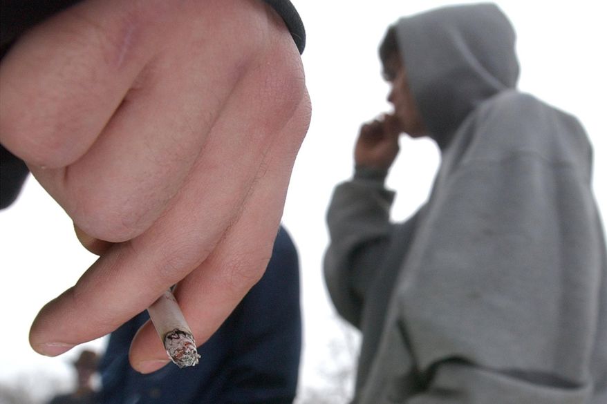 FILE - In this Tuesday, Dec. 10, 2002 file photo, a high school junior holds a cigarette as another high school student takes a drag in Lawrence, Kan. The smoking rate among U.S. high school and middle school students has been flat for three years now, after a fairly steady decline for nearly two decades, according to new numbers released Monday, Feb. 11, 2019. (Thad Allender/The Lawrence Journal-World via AP)