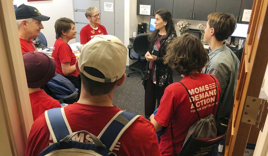 In this Tuesday, Feb. 5, 2019 photo, advocates for new gun safety regulations encircle New Mexico Democratic state Sen. Linda Lopez, center rear, of Albuquerque at her office at the New Mexico Statehouse in Santa Fe, N.M. An ambitious slate of Democrat-backed bills related to firearms and school safety could vault New Mexico to the forefront of efforts by states to stem gun violence through new legislation. (AP Photo/Morgan Lee)