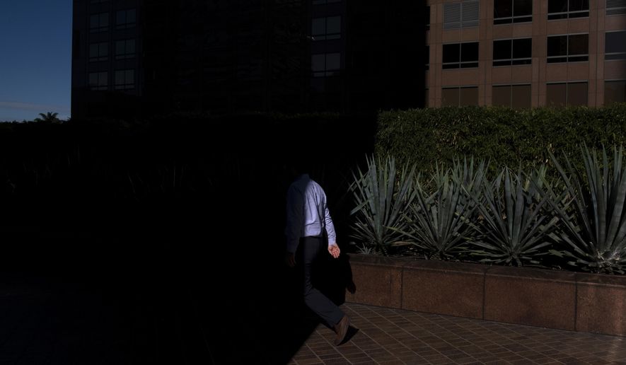 FILE- In this Dec. 4, 2018, file photo a man walks into the shade of a building in downtown Los Angeles. When deciding whether to buy, skip or toss an item, minimalists try to determine whether it adds value to their lives. Apply minimalism to your financial life, and you can shed outdated obligations and reduce stress. (AP Photo/Jae C. Hong, File)