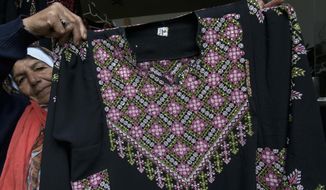 In this Monday, Jan. 28, 2019, file photo, Samiha Jeheshat, displays a handmade embroidered Palestinian thobe at her showroom in the West Bank village of Idna, north of Hebron. The thobe is gaining prominence as a softer symbol of Palestinian nationalism, competing with the classic keffiyeh. Rashida Tlaib proudly wore her thobe to her historic swearing-in as the first Palestinian American member of Congress, inspiring women around the world to tweet photos of themselves in their ancestral robes. (AP Photo/Nasser Nasser)