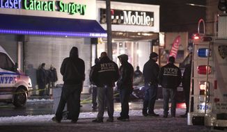 Investigators look over the area after a few New York City police officers were shot while responding to a robbery at a T-Mobile store in the Queens borough of New York on Tuesday, Feb. 12, 2019. (AP Photo/Kevin Hagen)