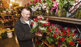 Larry Dominick, who helps out during busy times, looks over some rose bouquets in the flower cooler as he gets orders ready to go out for delivery on Valentine&#39;s Day at Welborn Floral &amp; Events in Owensboro, Ky., on Wednesday, Feb. 13, 2019. (Alan Warren/The Messenger-Inquirer via AP)