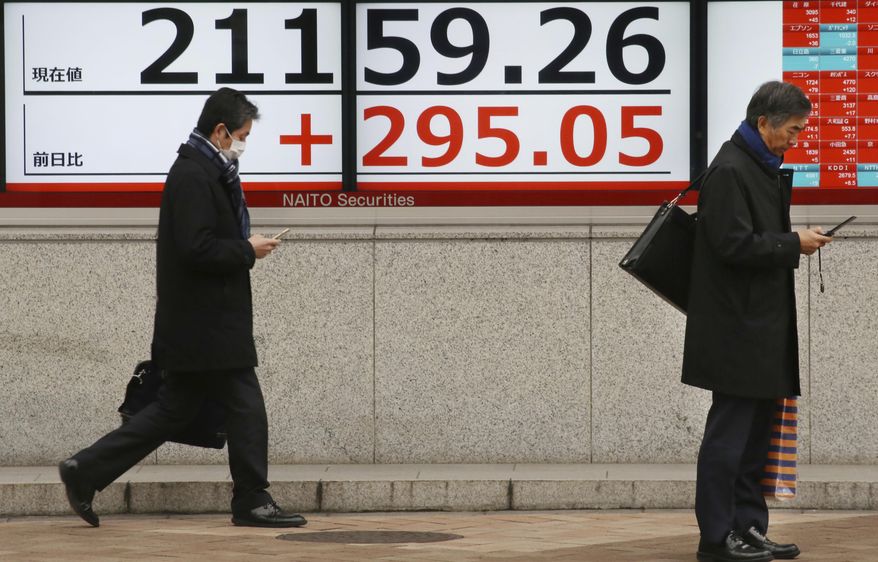 People walk by an electronic stock board of a securities firm in Tokyo, Wednesday, Feb. 13, 2019. Asian shares were mostly higher Wednesday, cheered by prospects for a resolution to the costly trade dispute between the U.S. and China, which had also sent Wall Street indexes higher. (AP Photo/Koji Sasahara)