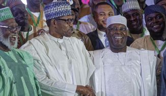 Incumbent President Muhammadu Buhari, left, shakes hands with opposition presidential candidate Atiku Abubakar after signing an electoral peace accord at a conference center in Abuja, Nigeria Wednesday, Feb. 13, 2019. Nigeria is due to hold general elections on Saturday, Feb. 16, 2019. (AP Photo/Ben Curtis)