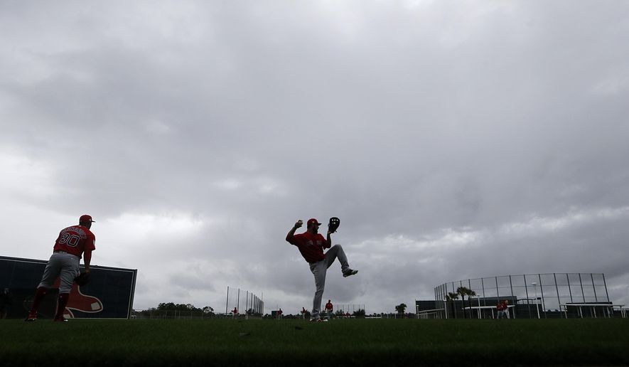 Boston Red Sox relief pitcher Brandon Workman, center, warms up in the rain as pitchers and catchers report for their first workout at their spring training baseball facility in Ft. Myers, Fla., Wednesday, Feb. 13, 2019. (AP Photo/Gerald Herbert)