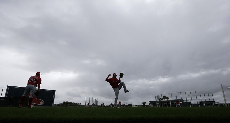 Boston Red Sox relief pitcher Brandon Workman, center, warms up in the rain as pitchers and catchers report for their first workout at their spring training baseball facility in Ft. Myers, Fla., Wednesday, Feb. 13, 2019. (AP Photo/Gerald Herbert)