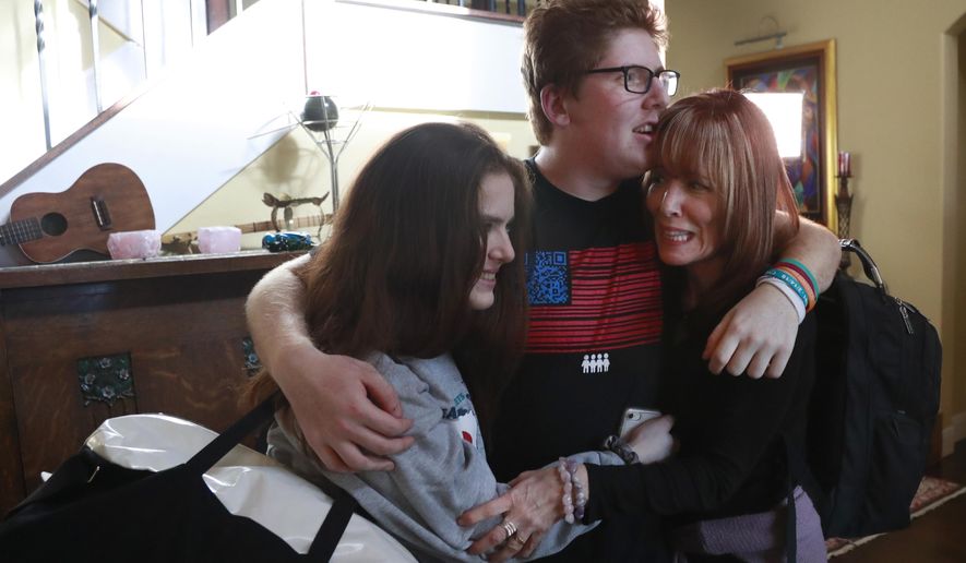 In this, Thursday, Feb. 7, 2019 photo, Matt Deitsch, center, hugs his sister Sam, left, and mother Elizabeth, as Elizabeth prepares to take Sam to the airport on for a speaking engagement in Washington, from their home in Parkland, Fla. Matt, Sam and their brother Ryan have crisscrossed the country helping to register young voters and advocate for stricter gun laws. (AP Photo/Wilfredo Lee)