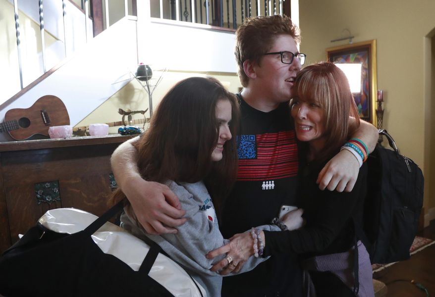 In this, Thursday, Feb. 7, 2019 photo, Matt Deitsch, center, hugs his sister Sam, left, and mother Elizabeth, as Elizabeth prepares to take Sam to the airport on for a speaking engagement in Washington, from their home in Parkland, Fla. Matt, Sam and their brother Ryan have crisscrossed the country helping to register young voters and advocate for stricter gun laws. (AP Photo/Wilfredo Lee)