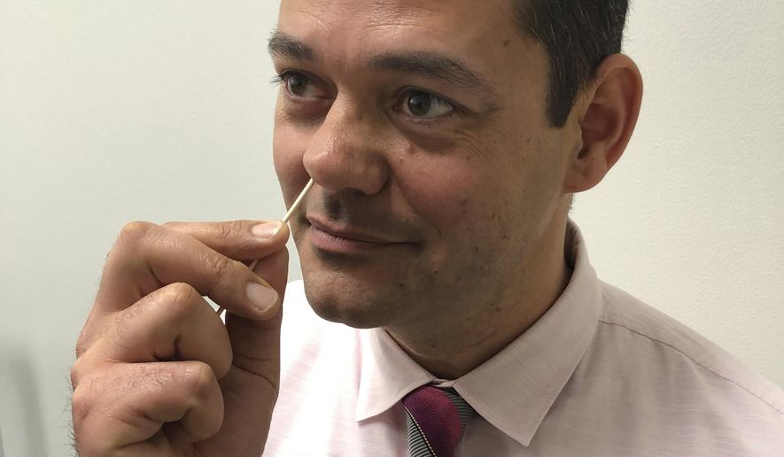 In this Monday, Feb. 11, 2019 photo provided by Dr. Susan Huang of the University of California, Irvine School of Medicine, researcher Raheeb Saavedra demonstrates how to use a medicated ointment for a study on preventing superbug infections. Hospitalized patients who harbor superbugs can cut their risk of developing full-blown infections if they swab medicated goo in their nose and use special soap and mouthwash for six months after going home, a study published on Wednesday, Feb. 13, 2019 finds. (Susan Huang via AP)