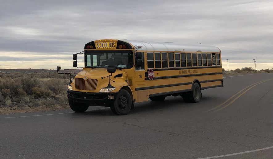 A school bus evacuates students from Sue V. Cleveland High School in Rio Rancho, New Mexico, on Thursday, Feb. 14, 2019, after a shot was fired on the campus. Police and school officials said no one was injured and a suspect was taken into custody. (AP/Russell Contreras)