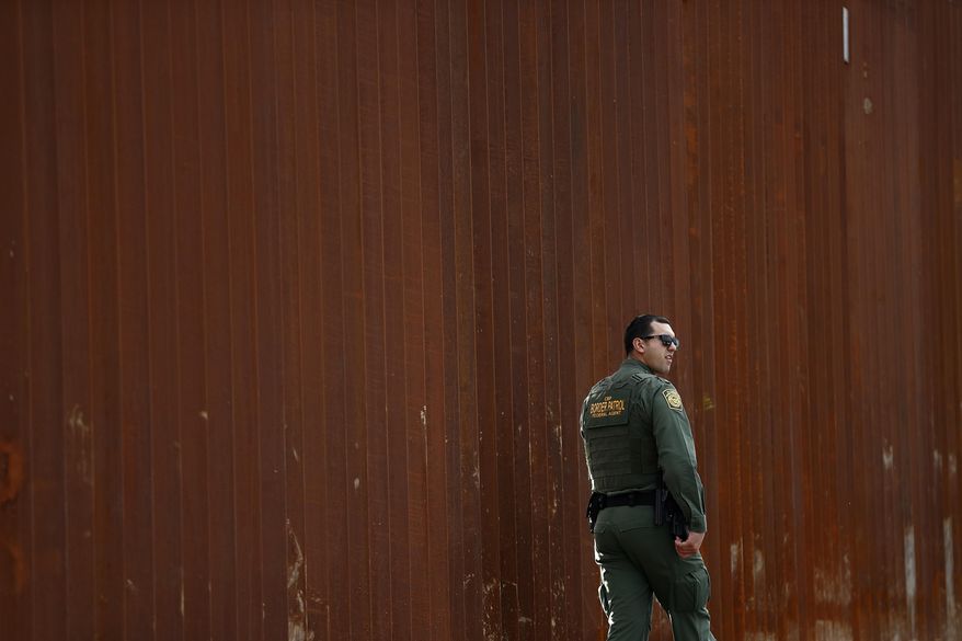 FILE - In this Jan 15, 2019, file photo, a U.S. Border Patrol agent walks in front of a section of newly-replaced border wall in San Diego. President Donald Trump would be taking an extraordinary step by declaring a national emergency to steer money to his promised border wall. He’s making it sound quite ordinary. (AP Photo/Gregory Bull, File)