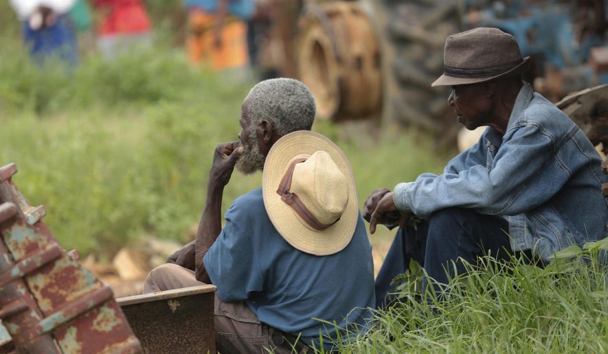 Relatives of trapped miners look on, near a mineshaft where some tens of artisanal gold miners are feared dead after rains flooded the mines while they were underground on the outskirts of Kadoma town about 200 kilometres west of Harare, Zimbabwe, Thursday, Feb, 14, 2019. Hopes of rescuing the trapped miners are fading due to lack of necessary equipment after they were reported missing Wednesday.(AP Photo/Tsvangirayi Mukwazhi)