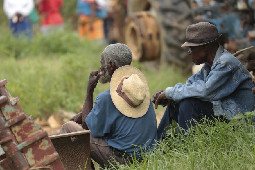 Relatives of trapped miners look on, near a mineshaft where some tens of artisanal gold miners are feared dead after rains flooded the mines while they were underground on the outskirts of Kadoma town about 200 kilometres west of Harare, Zimbabwe, Thursday, Feb, 14, 2019. Hopes of rescuing the trapped miners are fading due to lack of necessary equipment after they were reported missing Wednesday.(AP Photo/Tsvangirayi Mukwazhi)