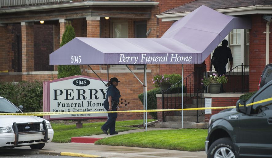 FILE - In this Friday, Oct. 19, 2018 file photo, Detroit Police walk into the Perry Funeral Home in Detroit, where police removed the remains of fetuses. Michigan regulators are seeking to revoke the licenses of the Detroit funeral home and its manager after the discovery of 63 fetuses in boxes and freezers last year. The Department of Licensing and Regulatory Affairs said Friday, Feb. 15, 2019, it completed an administrative investigation stemming from its inspection and shutdown of the Perry Funeral Home in October. (John T. Greilick/Detroit News via AP, File)