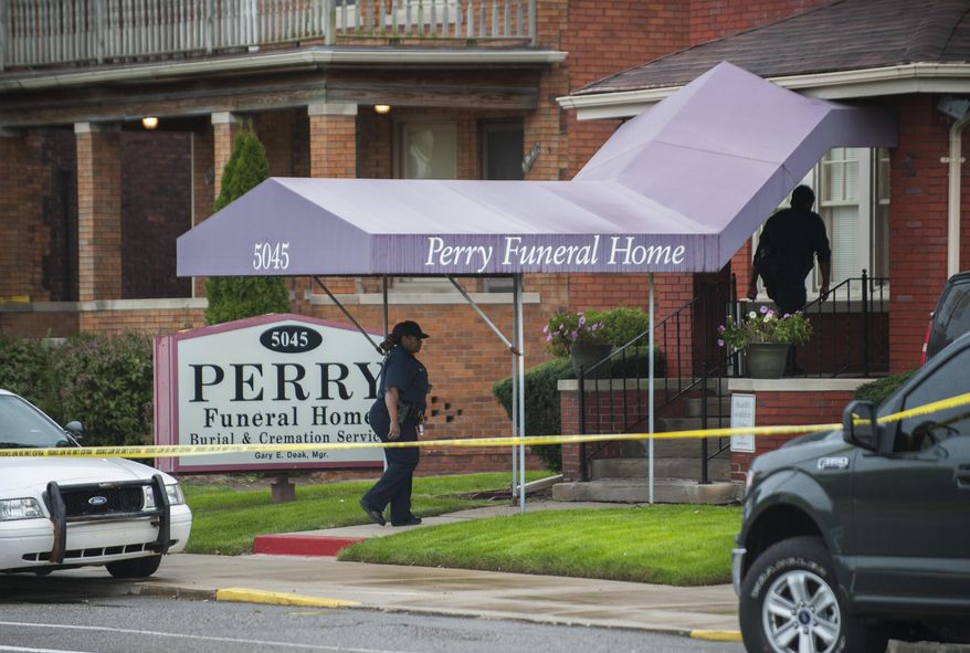 FILE - In this Friday, Oct. 19, 2018 file photo, Detroit Police walk into the Perry Funeral Home in Detroit, where police removed the remains of fetuses. Michigan regulators are seeking to revoke the licenses of the Detroit funeral home and its manager after the discovery of 63 fetuses in boxes and freezers last year. The Department of Licensing and Regulatory Affairs said Friday, Feb. 15, 2019, it completed an administrative investigation stemming from its inspection and shutdown of the Perry Funeral Home in October. (John T. Greilick/Detroit News via AP, File)