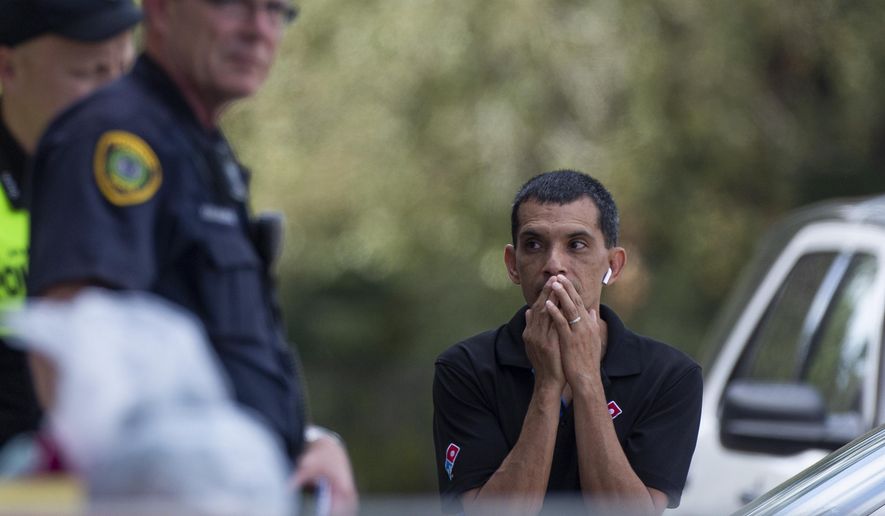 A man watches as the Houston Police officers investigate the scene of a fatal shooting at the Dunkin' Donuts on the 5800 block of Memorial Drive Friday, Feb. 15, 2019, in Houston. (Godofredo A. Vasquez/Houston Chronicle via AP)