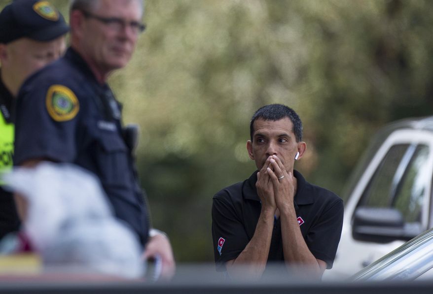 A man watches as the Houston Police officers investigate the scene of a fatal shooting at the Dunkin' Donuts on the 5800 block of Memorial Drive Friday, Feb. 15, 2019, in Houston. (Godofredo A. Vasquez/Houston Chronicle via AP)