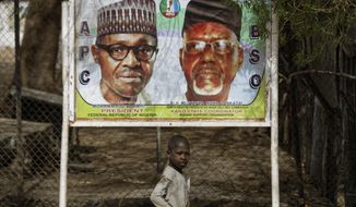 A young boy scavenges for re-sellable items from garbage on the streets, as he walks past a sign showing incumbent President Muhammadu Buhari, left, and local party official Mustapha Dankadai, right, in Kano, northern Nigeria Friday, Feb. 15, 2019. Nigeria is due to hold general elections on Saturday, pitting incumbent President Muhammadu Buhari against leading opposition presidential candidate Atiku Abubakar. (AP Photo/Ben Curtis)