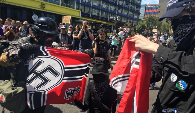FILE - In this Aug. 4, 2018, file photo, counter protesters tear a Nazi flag, in Portland, Ore. A member of Portland&#x27;s city council says she is shocked by a newspaper report that the commander for the police rapid response team exchanged friendly text messages with a leader of far-right protests that have rocked the city. Councilwoman Jo Ann Hardesty said the reporting in Willamette Week on Thursday, Feb. 14, 2019, confirms there are members of the Portland police force who work in collusion with right-wing extremists. (AP Photo/Manuel Valdes, File)