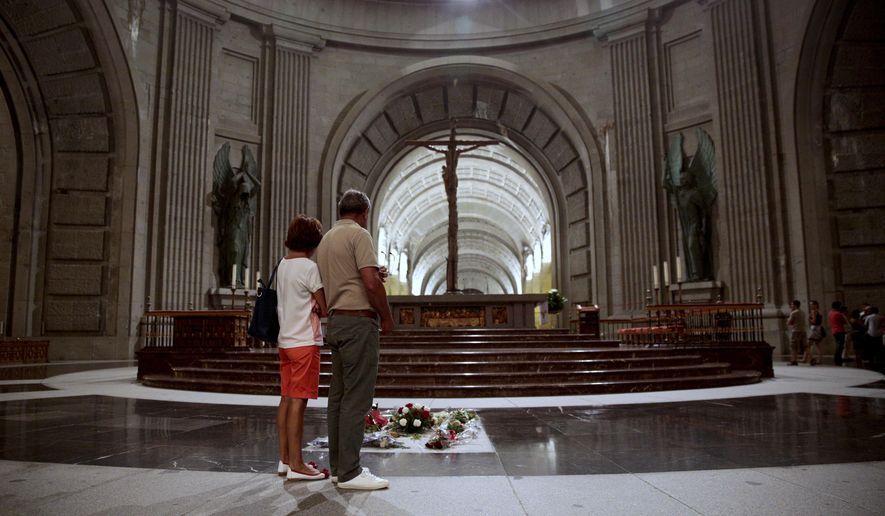 FILE - In this file photo taken on Friday, July 13, 2018, people look at the tomb of former Spanish dictator Francisco Franco inside the basilica at the Valley of the Fallen monument near El Escorial outside Madrid. Spanish authorities are giving Gen. Francisco Franco’s descendants a 15-day deadline to find a new burial place for the former dictator before his remains are exhumed from a lavish mausoleum it was reported on Friday, Feb. 15, 2019. Justice Minister Dolores Delgado says the new location can’t be a crypt under Madrid’s Almudena cathedral, where Franco’s relatives own a tomb. (AP Photo/Andrea Comas, File)
