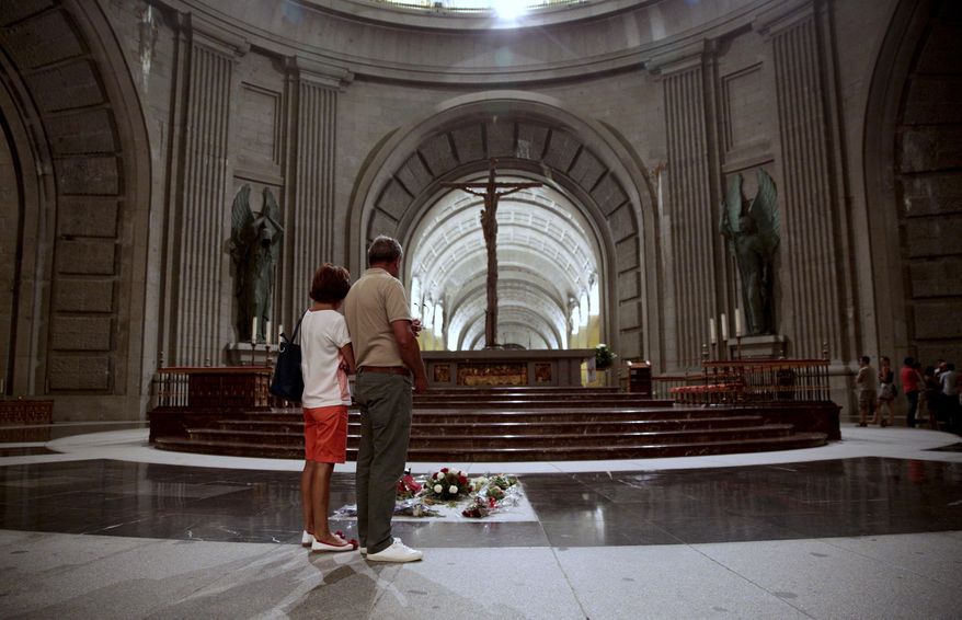 FILE - In this file photo taken on Friday, July 13, 2018, people look at the tomb of former Spanish dictator Francisco Franco inside the basilica at the Valley of the Fallen monument near El Escorial outside Madrid. Spanish authorities are giving Gen. Francisco Franco’s descendants a 15-day deadline to find a new burial place for the former dictator before his remains are exhumed from a lavish mausoleum it was reported on Friday, Feb. 15, 2019. Justice Minister Dolores Delgado says the new location can’t be a crypt under Madrid’s Almudena cathedral, where Franco’s relatives own a tomb. (AP Photo/Andrea Comas, File)