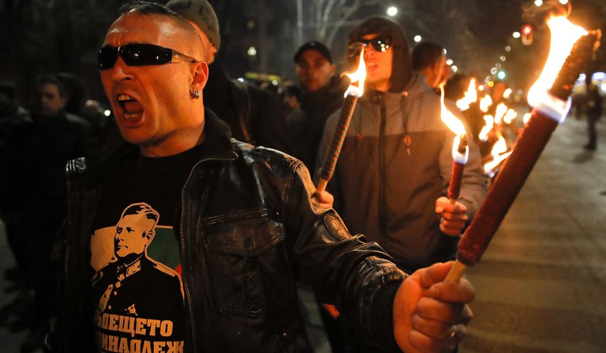 A man holds a flare chanting the name of Gen. Hristo Lukov, who had supported Germany during the Second World War, depicted on his t-shirt, as people take part in the "Lukov March," staged by the far-right Bulgarian National Union, in Sofia, Bulgaria, Saturday, Feb. 16, 2019. Bulgarian nationalists have marched through Sofia, the country's capital, to honor a World War II general known for his anti-Semitic and pro-Nazi activities. The annual Lukov March, staged by the far-right Bulgarian National Union, attracted hundreds of dark-clad supporters who walked through downtown Sofia holding torches and Bulgarian flags and chanting nationalist slogans. (AP Photo/Vadim Ghirda)