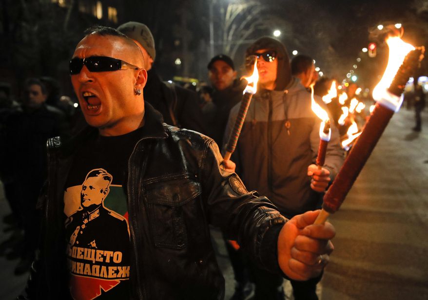 A man holds a flare chanting the name of Gen. Hristo Lukov, who had supported Germany during the Second World War, depicted on his t-shirt, as people take part in the "Lukov March," staged by the far-right Bulgarian National Union, in Sofia, Bulgaria, Saturday, Feb. 16, 2019. Bulgarian nationalists have marched through Sofia, the country's capital, to honor a World War II general known for his anti-Semitic and pro-Nazi activities. The annual Lukov March, staged by the far-right Bulgarian National Union, attracted hundreds of dark-clad supporters who walked through downtown Sofia holding torches and Bulgarian flags and chanting nationalist slogans. (AP Photo/Vadim Ghirda)