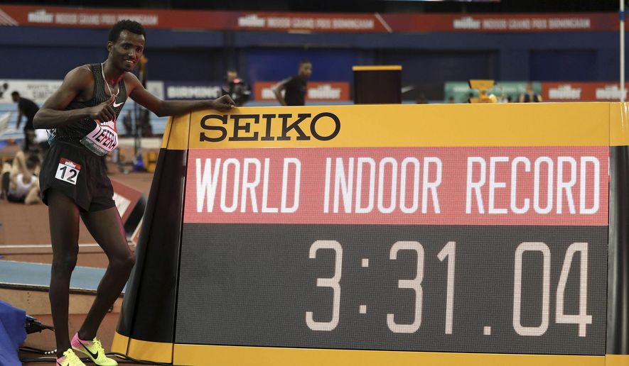 Ethiopia's Samuel Tefera poses next to teh time indicator, as he celebrates getting the mens 1500 metre World Indoor Record during the Muller Indoor Grand Prix in Birmingham, England, Saturday Feb. 16, 2019. (David Davies/PA via AP)