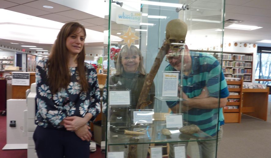 This Thursday Jan. 17, 2019 photo shows Ohio County Public Library staff members, from left, Erin Rothenbuehler, Dottie Thomas and Sean Duffy examine a new exhibit, &amp;quot;Wheeling in 250 Objects,&amp;quot; at the library in Wheeling W.Va.. The major exhibit coincides with Wheeling 250, a year-long celebration of the 250th anniversary of the city&#x27;s founding. (Linda Cumins/The Intelligencer via AP)
