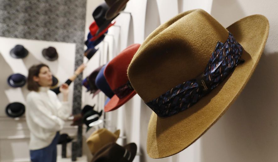 A woman looks at hats in a Borsalino store in downtown Milan, Italy, Wednesday, Jan. 16, 2019. If the traditional Italian hat-maker Borsalino was once synonymous with the fedora, its new private equity owners want to imbue the brand with cachet that extends to couture, sportswear and streetwear for women and Millennials -- without alienating its classic customers and the silhouette that helped shape the rough-and-tumble images of Robert Redford, Frank Sinatra and, perhaps no one more than, Humphrey Bogart. (AP Photo/Antonio Calanni)