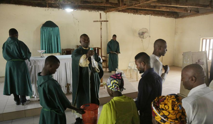 Rev. Father Maurice Kwairanga, center, blesses parishioner during a Mass at St. Charles Catholic Church, in Ngurore, Nigeria, Sunday, Feb. 17, 2019. (AP Photo/ Sunday Alamba) **FILE**
