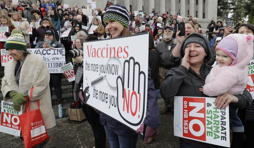 Lacey Walter, of Kennewick, Wash., holds a sign that reads &quot;Vaccines, the more you know, the more you No!&quot; as she takes part in a rally held in opposition to a proposed bill that would remove parents&#39; ability to claim a philosophical exemption to opt their school-age children out of the combined measles, mumps and rubella vaccine, Friday, Feb. 8, 2019, at the Capitol in Olympia, Wash. Amid a measles outbreak that has sickened people in Washington state and Oregon, lawmakers earlier Friday heard public testimony on the bill. (AP Photo/Ted S. Warren)