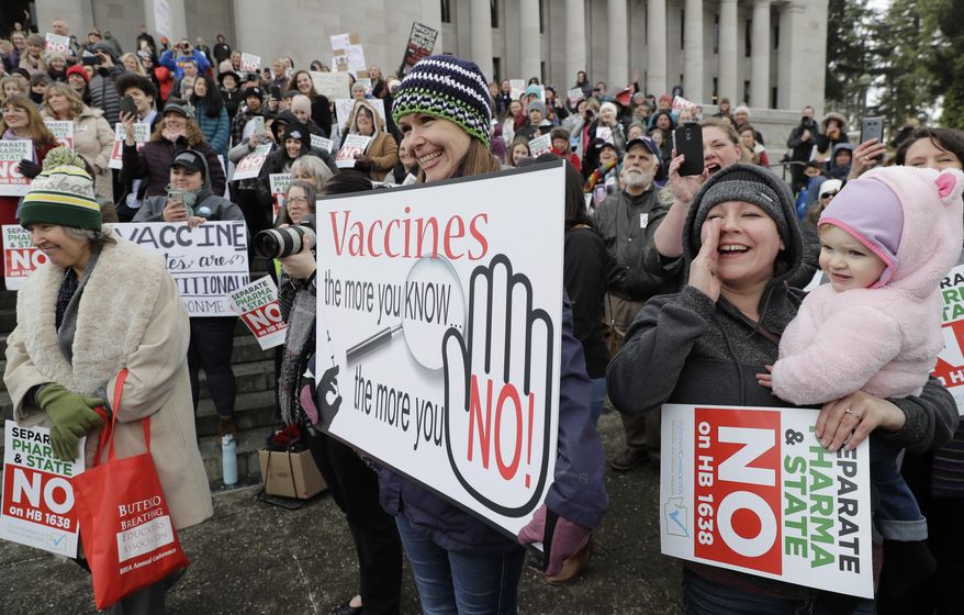 Lacey Walter, of Kennewick, Wash., holds a sign that reads &quot;Vaccines, the more you know, the more you No!&quot; as she takes part in a rally held in opposition to a proposed bill that would remove parents&#39; ability to claim a philosophical exemption to opt their school-age children out of the combined measles, mumps and rubella vaccine, Friday, Feb. 8, 2019, at the Capitol in Olympia, Wash. Amid a measles outbreak that has sickened people in Washington state and Oregon, lawmakers earlier Friday heard public testimony on the bill. (AP Photo/Ted S. Warren)