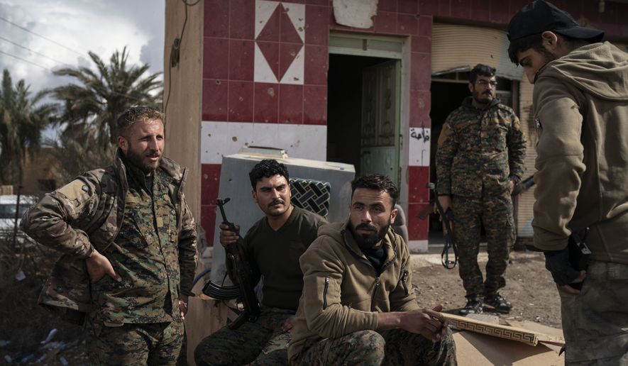 U.S.-backed Syrian Democratic Forces (SDF) fighters stand outside a building used as a temporary base near the last land still held by Islamic State militants in Baghouz, Syria, Monday, Feb. 18, 2019. Hundreds of Islamic State militants are surrounded in a tiny area in eastern Syria are refusing to surrender and are trying to negotiate an exit, Syrian activists and a person close to the negotiations said Monday. (AP Photo/Felipe Dana)