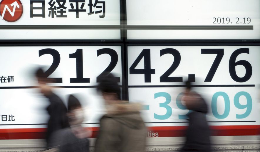 People walk past an electronic stock board showing Japan's Nikkei 225 index at a securities firm in Tokyo Tuesday, Feb. 19, 2019. Asian shares are mostly higher as Chinese and U.S. officials prepare for trade talks in Washington this week. (AP Photo/Eugene Hoshiko)