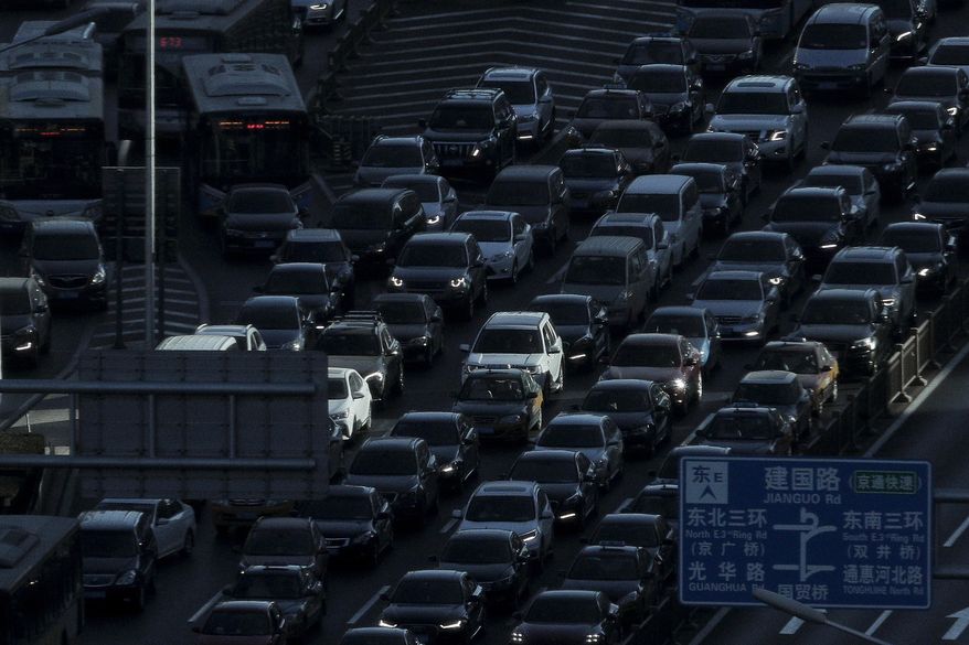 FILE - In this Dec. 11, 2018, file photo, a beam of sunlight is cast on vehicles on a city ring-road clogged with heavy traffic during the morning rush hour in Beijing. China’s auto sales fell for an eighth month in January, 2019, extending a painful decline for the biggest global market. (AP Photo/Andy Wong, File)