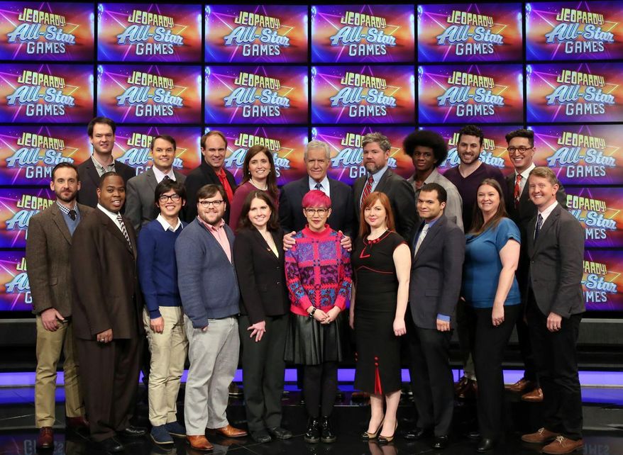 This image released by Jeopardy Productions, Inc. shows, front row from left, Brad Rutter, Colby Burnett, Alan Lin, Seth Wilson, Larissa Kelly, Monica Thieu, Pam Mueller, Matt Jackson, Jennifer Giles and Ken Jennings, back row from left, Ben Ingram, Roger Craig, David Madden, Julia Collins, host Alex Trebek, Austin Rogers, Leonard Cooper, Alex Jacob and Buzzy Cohen on the set of the game show "Jeopardy!" The game show’s first-ever team tournament will pit groups of former champions against each other in 10 weekday episodes airing from Wednesday, Feb. 20, to Tuesday, March 5. (Jeopardy Productions, Inc. via AP)