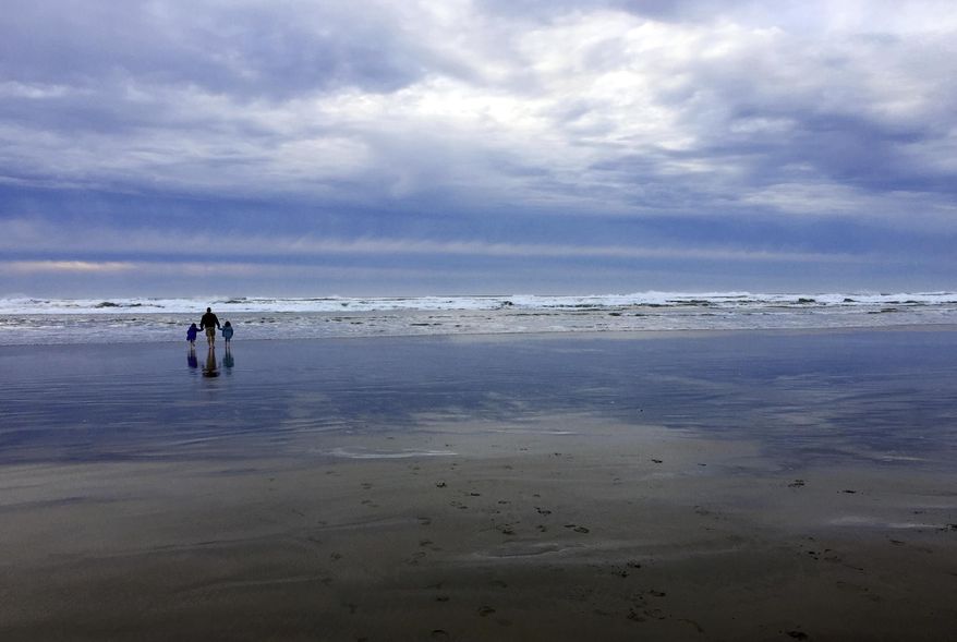 In this Jan. 14, 2018 photo, a family walks on the beach at Fort Stevens State Park near Astoria, Ore. Fort Stevens is one of three state parks that collectively accounted for more than half of the increase in overnight camping stays at Oregon's parks. Oregon set a record in 2018 with 2.9 million campers and had the second-highest number ever of total visitors with 54 million people. (AP Photo/Gillian Flaccus)