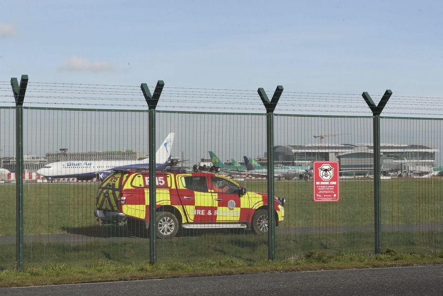An emergency service vehicle by the perimeter fence after a confirmed drone sighting forced the temporary suspension of operations at Dublin Airport, Ireland, Thursday Feb. 21, 2019. Flights at Dublin Airport were grounded for a short time Thursday, to ensure the safety and security of passengers after a confirmed drone sighting. (Nial Carson/PA via AP)