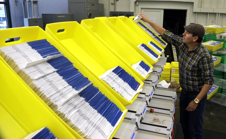 FILE - In this Nov. 3, 2014, file photo, Diego Valencia processes Oregon ballots at Multnomah County election headquarters in Portland, Ore. Oregon Gov. Kate Brown is touting a new report that found nearly 78,000 Oregonians who are 16 and 17 were pre-registered to vote under the state's automatic voter registration law. The law, which is seen as a national model for voter participation, automatically signs Oregonians up to vote when they get a driver's license. (AP Photo/Don Ryan, File)