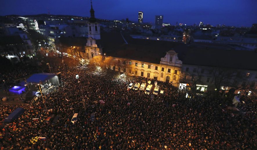 People gather on a square during a rally to mark one year anniversary of the slayings of an investigative reporter and his fiancee, in Bratislava, Slovakia, Thursday, Feb. 21, 2019. Jan Kuciak and Martina Kusnirova were shot dead in their home on Feb. 21 last year. People used the anniversary on Thursday to press for the investigation to be completed. (AP Photo/Petr David Josek)