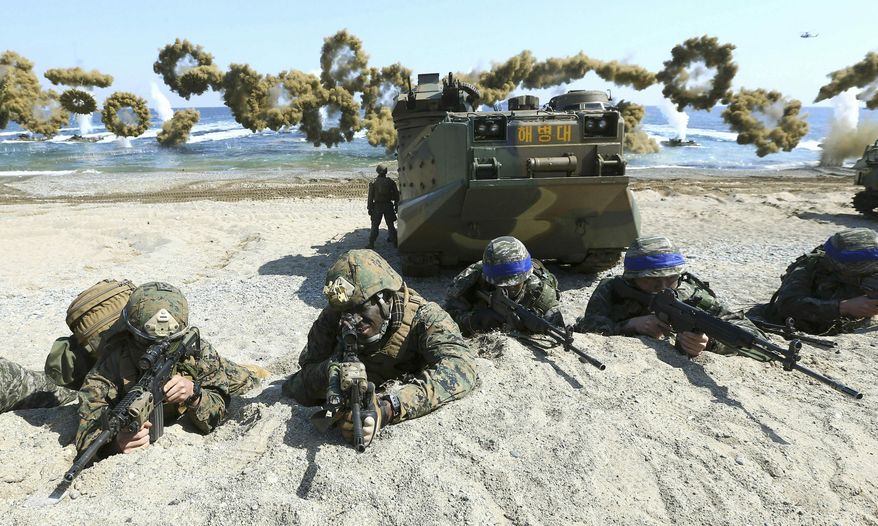 In this March 12, 2016, photo, Marines of the U.S., left, and South Korea, wearing blue headbands on their helmets, take positions after landing on a beach during the joint military combined amphibious exercise, called Ssangyong, part of the Key Resolve and Foal Eagle military exercises, in Pohang, South Korea. (Associated Press) **FILE**