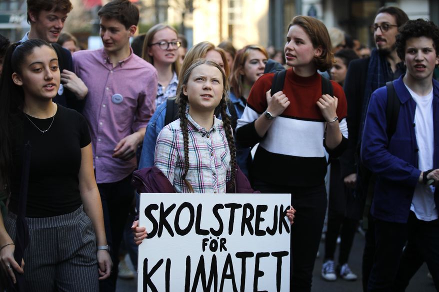 Swedish teenager Greta Thunberg, center, leads a march of thousands of French students through Paris, France, to draw more attention to fighting climate change, Friday, Feb. 22, 2019. Sign reads : "school strike for the climate". (AP Photo/Francois Mori)