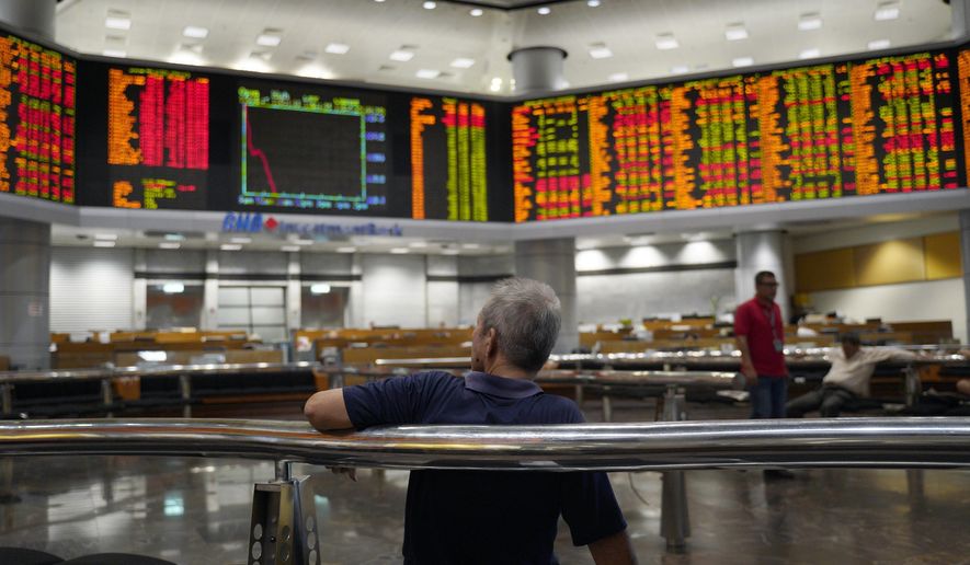 A visitor sits in front of private stock trading boards at a private stock market gallery in Kuala Lumpur, Malaysia, Friday, Feb. 22, 2019. Asian shares were mostly lower Friday after a slide on Wall Street as investors nervously watched the U.S.-China trade talks in Washington. (AP Photo/Yam G-Jun)