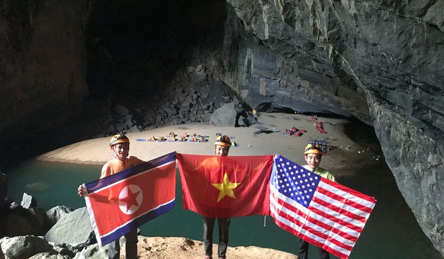 In this Monday, Feb. 15, 2019, drone image, cave explores pose with flags of North Korea, Vietnam and the U.S. in En cave in Quang Binh province, Vietnam. Vietnam will host the second summit between U.S. President Donald Trump and North Korean leader Kim Jong Un in Hanoi on Feb. 27-28. (Oxalis Adventure via AP)