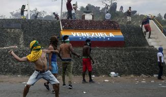 Venezuelan demonstrators throw stones during clashes with authorities, at the border between Brazil and Venezuela, Saturday, Feb.23, 2019. Tensions are running high in the Brazilian border city of Pacaraima. Thousands remained at the city&#39;s international border crossing with Venezuela to demand the entry of food and medicine.(AP Photo/Ivan Valencia)
