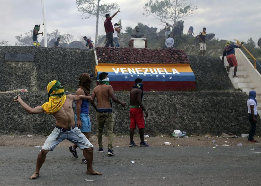 Venezuelan demonstrators throw stones during clashes with authorities, at the border between Brazil and Venezuela, Saturday, Feb.23, 2019. Tensions are running high in the Brazilian border city of Pacaraima. Thousands remained at the city&#x27;s international border crossing with Venezuela to demand the entry of food and medicine.(AP Photo/Ivan Valencia)